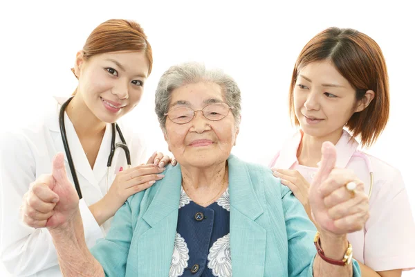 Sorrindo asiático equipe médica com mulher velha — Fotografia de Stock