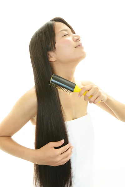 Beautiful woman brushing her hair — Stock Photo, Image