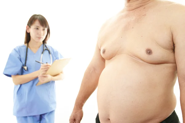 Серьезный врач, осматривающий ожирение пациента — стоковое фото