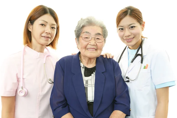 Asya sağlık personeli ile yaşlı kadın gülümsüyor — Stok fotoğraf