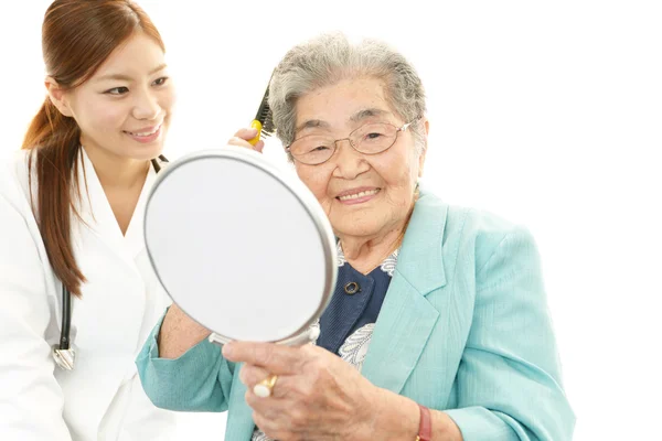 Sorridente medico asiatico e donna anziana — Foto Stock