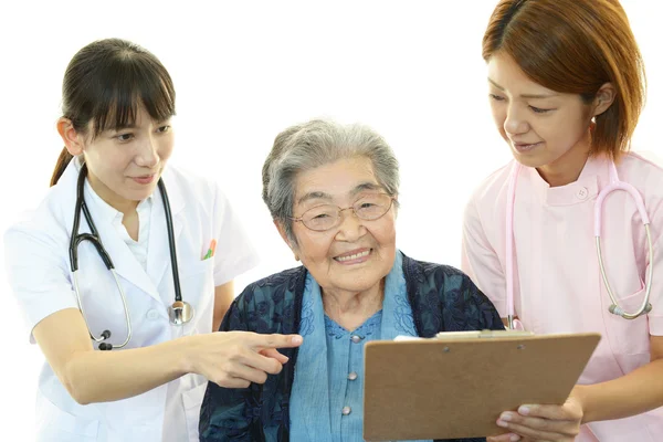 Smiling Asian medical staff with old woman — Stock Photo, Image