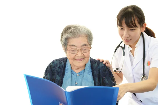 Sorridente medico asiatico e donna anziana — Foto Stock