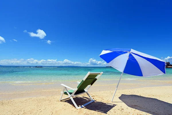 Strandparasol op een zonnig strand met de blauwe zee op de achtergrond. — Stockfoto