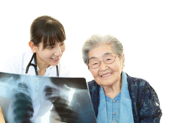 Sorridente medico asiatico e donna anziana — Foto Stock