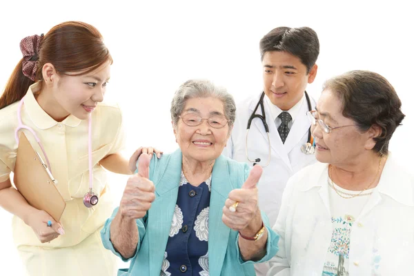 Asya sağlık personeli ile yaşlı kadın gülümsüyor — Stockfoto