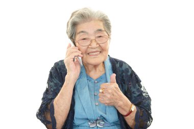Old woman holding a mobile phone and talking clipart