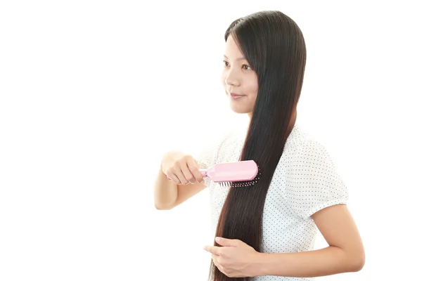 Beautiful woman brushing her hair — Stock Photo, Image