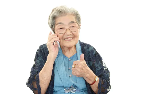 Mulher velha segurando um telefone celular e falando — Fotografia de Stock