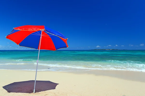 Het strand en het strand-paraplu van midzomer. — Stockfoto