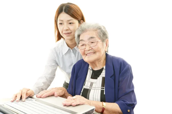 Old woman with laptop at the desk — Stock Photo, Image