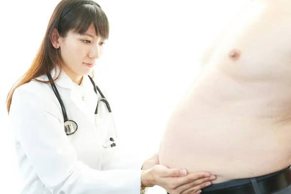 Серьезный врач, осматривающий ожирение пациента — стоковое фото