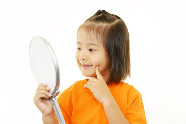 Маленькая девочка смотрит на себя в ручное зеркало — стоковое фото
