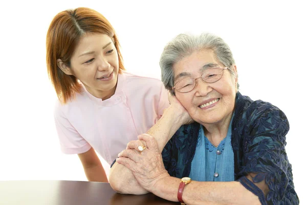 Vriendelijke verpleegster zorgt voor een oudere vrouw — Stockfoto