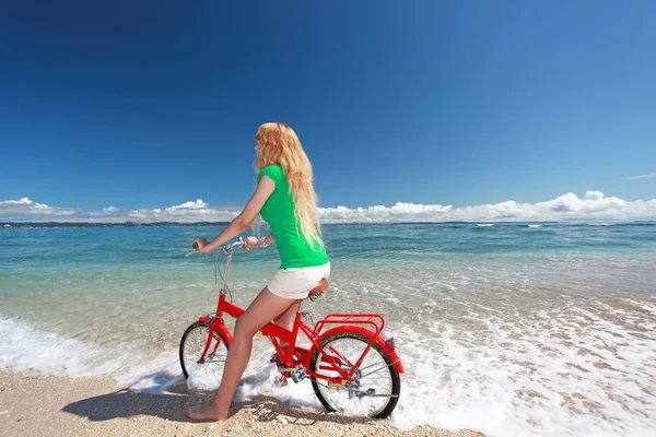 Młoda kobieta jeżdżąca na rowerze po plaży — Zdjęcie stockowe
