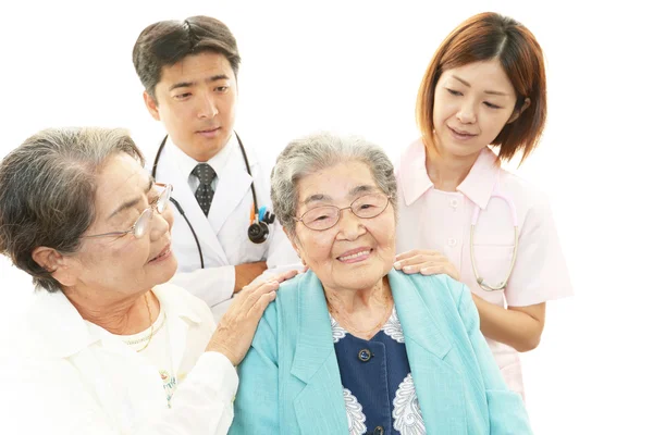 Smiling Asian medical staff with old women — Stock Photo, Image