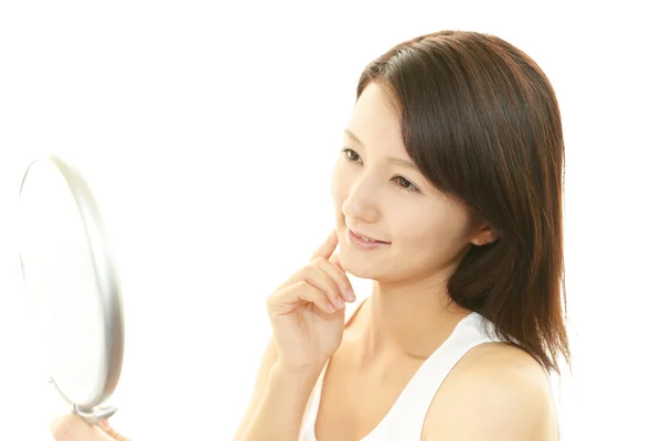 Beautiful young woman looking at herself in a hand mirror — Stock Photo, Image