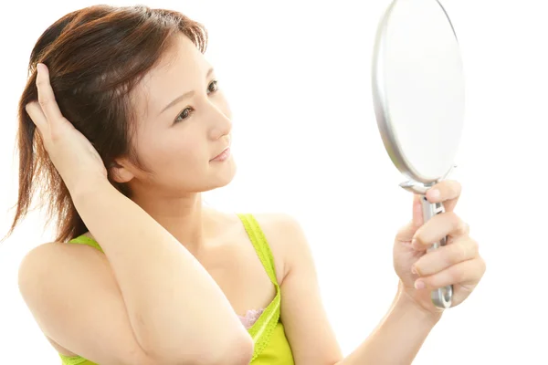 Woman looking at herself in a hand mirror — Stock Photo, Image