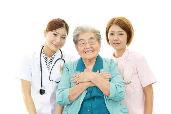 Sorrindo asiático equipe médica com mulher velha — Fotografia de Stock