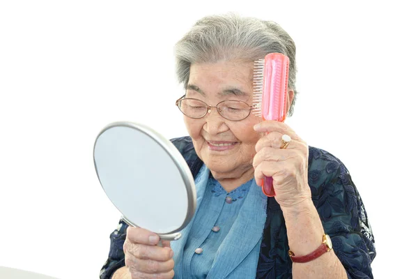 Oude vrouw het verzorgen van haar haren — Stockfoto