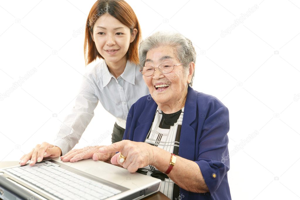 Teacher helping an elderly lady use a computer