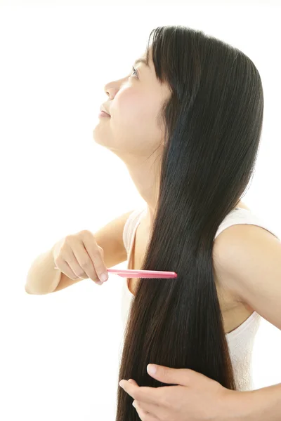 Joven mujer peinándose el pelo — Foto de Stock