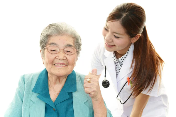 Sorridente medico asiatico e donna anziana — Foto Stock