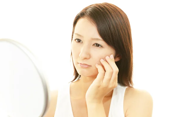 Woman looking at herself in a hand mirror — Stock Photo, Image