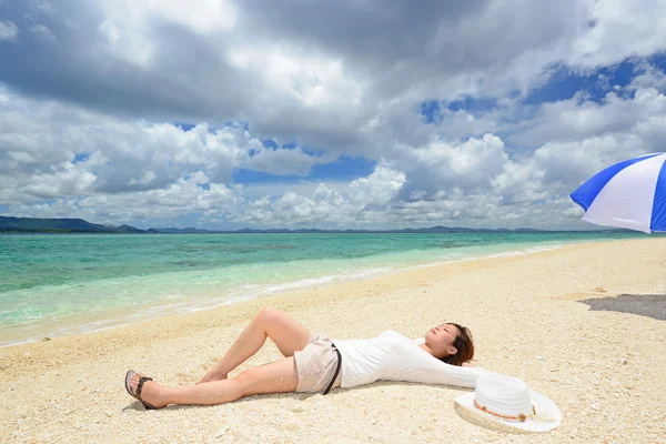 Ung kvinna ligger på stranden — Stockfoto