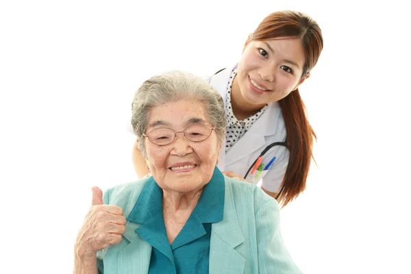 Lächelnd asiatisch medizinisches personal mit alt frau lizenzfreie Stockbilder
