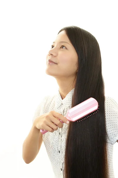 Mujer joven peinando con un cepillo de pelo — Foto de Stock