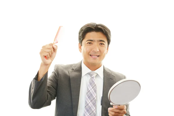 Uśmiechający się azjatycki biznesmen sprawdzanie jego wygląd — Zdjęcie stockowe