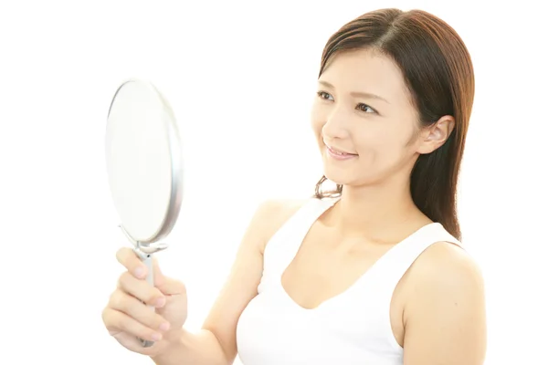 Mujer mirando su cara en un espejo — Foto de Stock