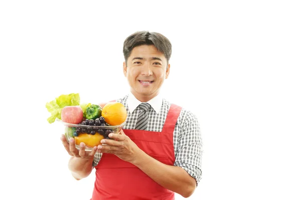 Hombre sonriente sosteniendo verduras con frutas — Foto de Stock