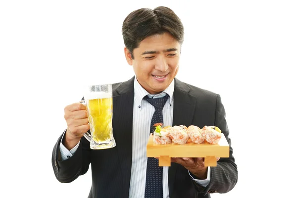 Geschäftsmann genießt Sushi und Bier — Stockfoto