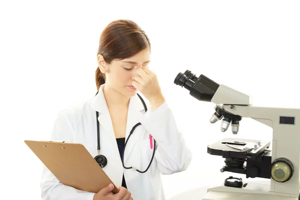Trött läkare med en mikroskopisk undersökning — Stockfoto