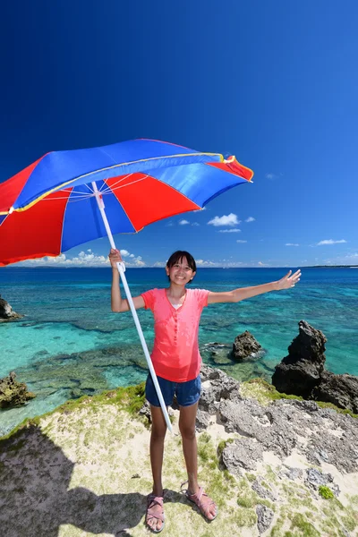 Flicka under parasollen på den vackra stranden — Stockfoto