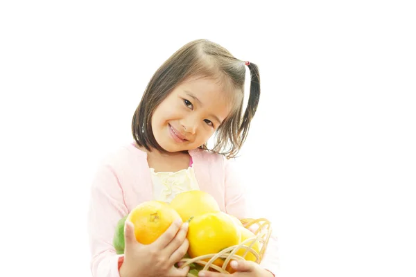 Ragazza sorridente che tiene frutta — Foto Stock