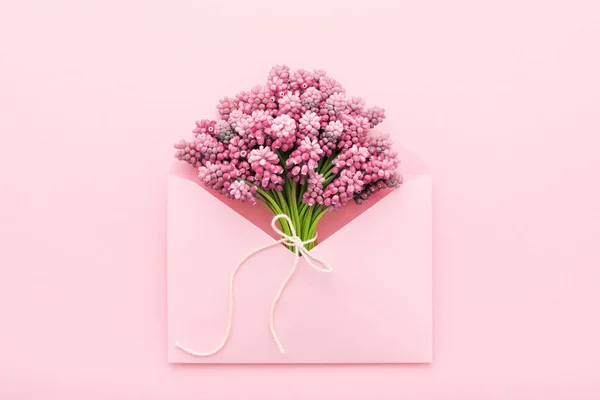 Spring flowers in a pink envelope for Mothers day, flat lay Royalty Free Stock Photos