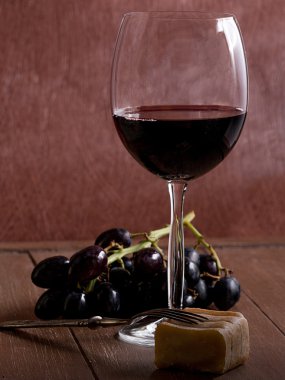bir bardak kırmızı şarap ile peynir ve üzüm