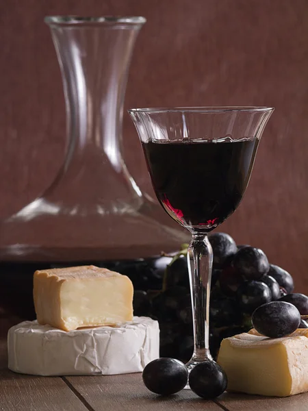 Una copa de vino tinto con queso y uvas —  Fotos de Stock