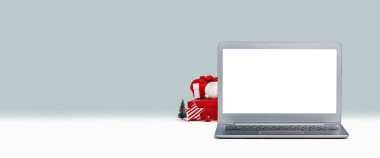 Masasında maket ekranı olan dizüstü bilgisayarın ön görüntüsü. Noel hediyeleri ve dizüstü bilgisayarın arkasındaki süslemeler. Tatil alışverişi ya da satış. İnternet ürünleri. Uzayı kopyala Ren geyiği, Noel ağacı.