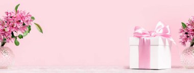 Hediye kutusu, bahar ya da yaz çiçeklerinin olduğu pembe bir bayram afişi. Tek renkli, doğum günü ya da düğün anneleri günü.
