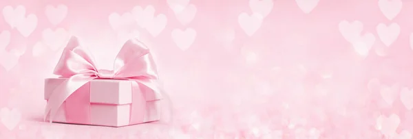 粉色礼品盒 带着闪亮的粉色丝带 点缀在粉色的心形背景上 礼物或假期的概念 母亲节 生日或情人节 带有复制空间 最小单色宽横幅 — 图库照片