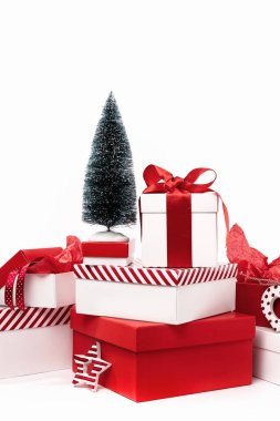 Beyaz arka planda Noel ağacı olan çeşitli kırmızı beyaz hediye kutuları. Çeşitli boyutlarda. Mutlu Noeller ve mutlu yıllar hediye alışverişi ve satış konsepti