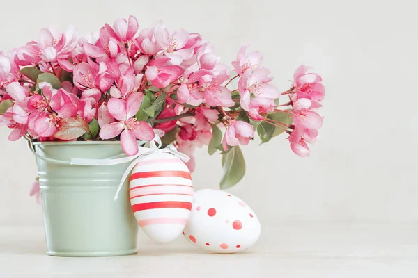 Весняні гілки квітучого дерева та великодні яйця у вазі на пастельному фоні Стокове Фото