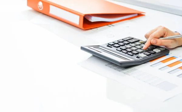 Фінанси. Жіноча рука з калькулятором на фінансових графах на столі Ліцензійні Стокові Фото
