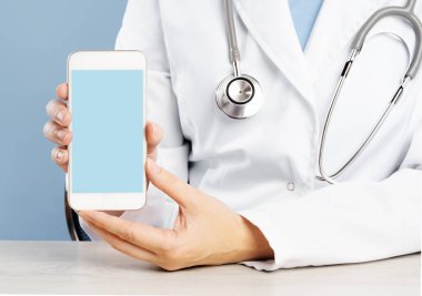 Doktor elinde tıbbi bir uygulama ile akıllı telefon tutuyor.