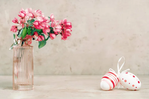 Lente bloeiende boomtakken en paaseieren in een vaas op pastelachtergrond Stockfoto