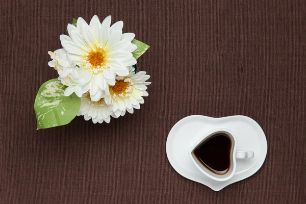 Coffee and white artificial flowers — Stock Photo, Image